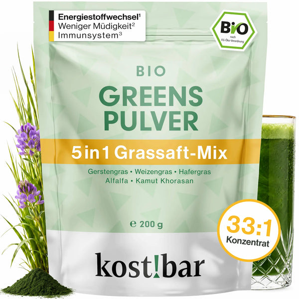 kost!bar BIO Greens Pulver Beutel 200 g neben einem Glas grünem Grassaft – Bio Gerstengras Grassaftpulver aus 5 Gräsern
